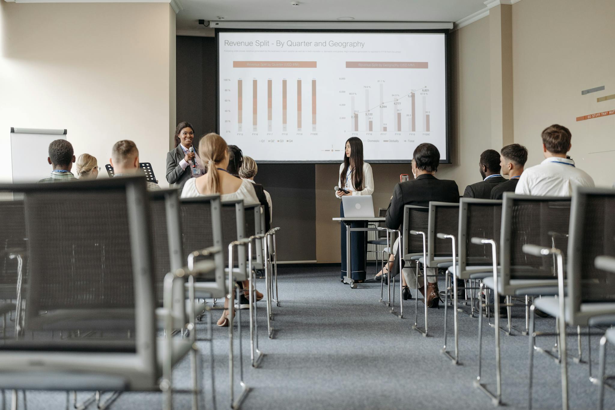 James Bleier Business conference attendees listen to a presentation on revenue split by quarter and geography.